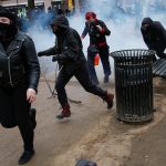 Activists race after being hit by a stun grenade while protesting against U.S. President-elect Donald Trump on the sidelines of the inauguration in Washington